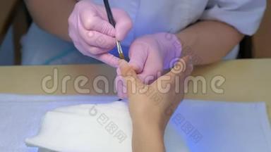 美甲大师是在美容诊所用刷子涂指甲凝胶紫胶。